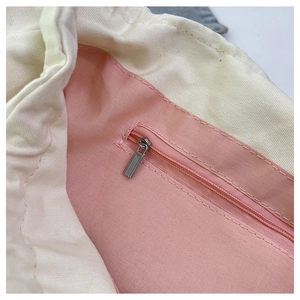 Vista interior del bolso de lona con forro rosa y bolsillo con cremallera de metal