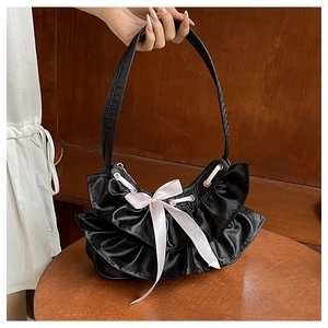Detail of black pleated satin shoulder bag with pink ribbon bow and silver eyelets