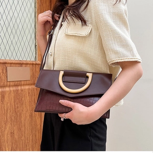 Detailed view of dark brown faux crocodile leather texture and gold metal buckle