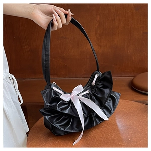 Detail of black satin shoulder bag featuring elegant ruffles and a pink silk bow accent