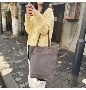 Detail of vintage gray canvas tote bag with brown leather straps and rivet pocket design