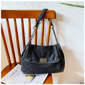 Nahaufnahme der Vintage-Umhängetasche aus Jeansstoff mit Kette auf einem Holzstuhl