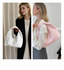 Detalle del bolso de media luna en blanco y rosa con una textura de cuero sintético suave