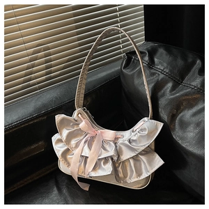 Detail view of silver metallic shoulder bag with ruffle trim and a pink silk bow