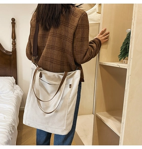 Detail of canvas tote bag showing adjustable brown shoulder strap and large side pocket