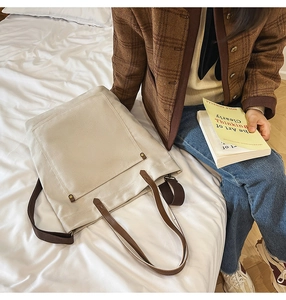 Detail of off-white canvas tote bag with brown leather straps and front pocket