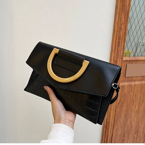 Detail of black crocodile texture clutch bag with yellow D-shaped resin handle