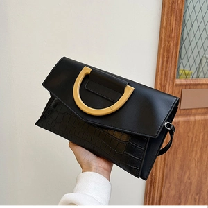 Detail of black crocodile texture bag featuring a unique yellow semi-circle handle and strap