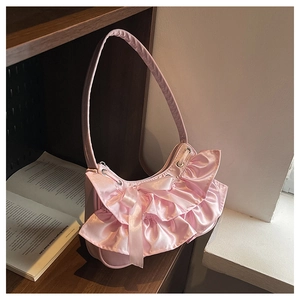 Detail of pink satin shoulder bag featuring soft ruffles and a central decorative bow