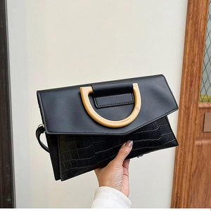 Detail of black crocodile texture leather and matte flap on envelope clutch bag