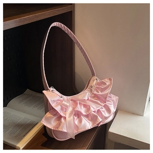 Close-up of pink satin underarm bag with layered ruffles and delicate silk bow detail