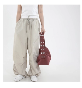 Detail of light beige baggy cargo pants featuring elastic drawstring waist and nylon texture