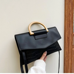 Detail view of black handbag showing smooth leather flap and crocodile pattern texture