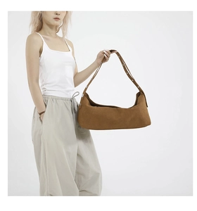 Brown suede crescent tote bag with adjustable strap worn with casual outfit