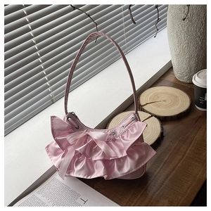 Close-up of pink hobo bag with satin ruffles, ribbon bows and mesh stitching details