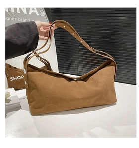 Detail of a brown suede crossbody bag with silver rivets on adjustable double straps