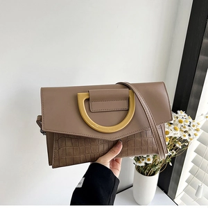 Detail of brown crocodile pattern clutch with large golden D-ring metal buckle