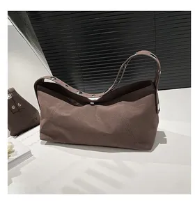 Detail view of dark brown canvas crossbody bag with metal rivets and fine stitching