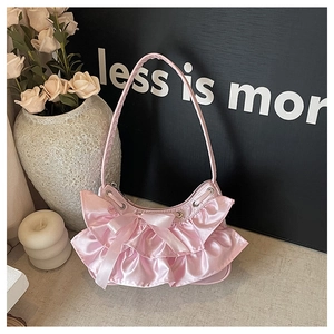 Detail of pink satin shoulder bag featuring layered ruffles and a delicate ribbon bow