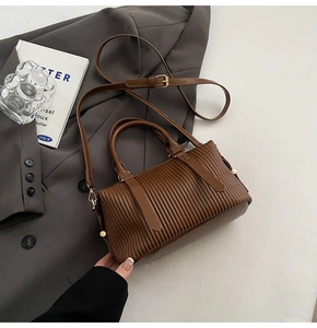 Close-up of brown pleated leather handbag with gold hardware and adjustable strap detail