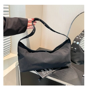 Close-up of black crossbody bag with silver rivet details on the shoulder strap