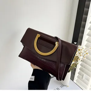 Detail of burgundy crocodile-embossed leather clutch with gold D-ring buckle