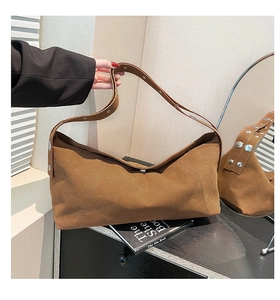 Detail showing the brown suede crossbody bag texture and silver rivet decorations on the strap