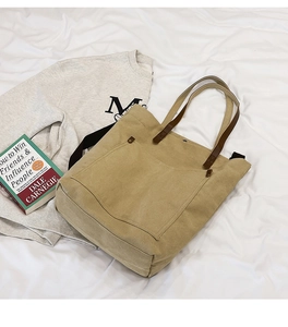 Detail of khaki canvas tote with brown leather handles and reinforced rivet pockets