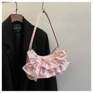 Close-up of pink satin shoulder bag with mesh ruffles and decorative silk bow detail