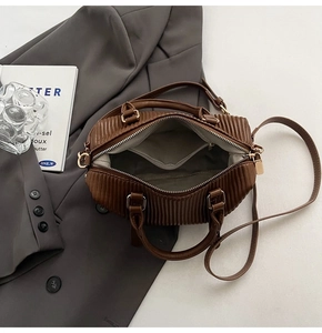 Detailed interior of brown pleated bucket bag showing metal zipper and grey fabric lining