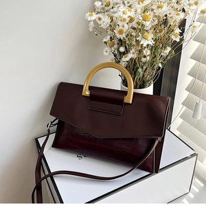 Detail of burgundy crocodile pattern handbag with amber resin handle on white display box