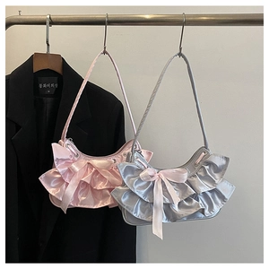 Detail of pink and silver satin armpit bags featuring layered ruffles and ribbon bows