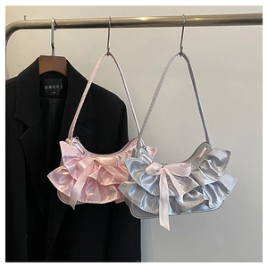 Detail of ruffle layers and ribbon bow on satin crescent underarm bag in pink and silver