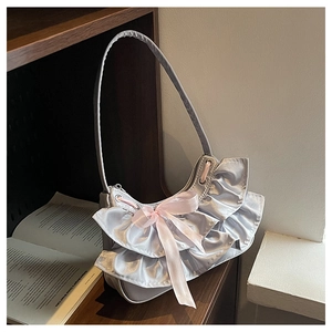 Detail of silver satin shoulder bag with double ruffles and pink bow by a vintage shelf