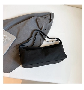 Close-up of a minimalist black canvas tote bag with reinforced handles and rivet details