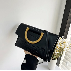Detail of black crocodile texture bag with gold D-clasp buckle and leather finish