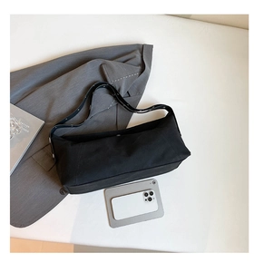 Flat lay of black fabric crossbody bag with metal buckle and size reference