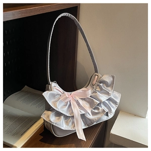 Detailed shot of silver crescent bag with pink satin bow and ruffle design details