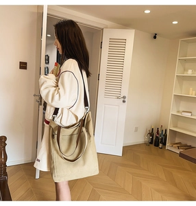 Detail of khaki canvas tote bag showing side stitching and adjustable brown shoulder strap