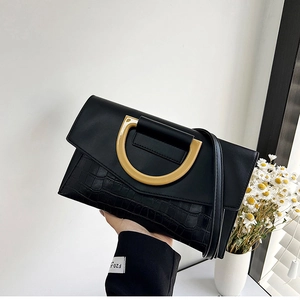 Close-up of black crocodile embossed leather handbag featuring a large golden D-ring buckle
