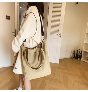 Detail of khaki canvas tote bag featuring brown top handles and adjustable shoulder strap