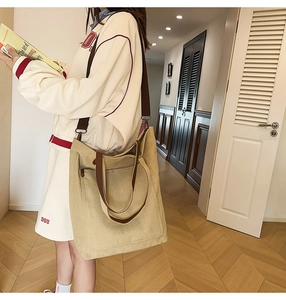 Beige washed canvas tote bag with adjustable brown strap shown in a casual lifestyle setting