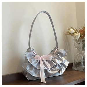 Detail view of silver mesh underarm bag with ruffled edges and pink satin bow accent