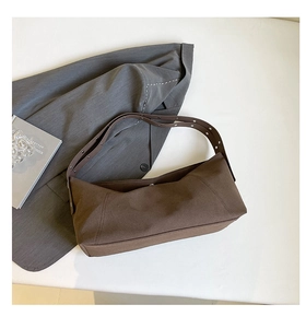 Detailed close-up of dark brown crossbody bag with silver metal grommets on shoulder strap