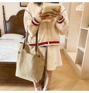 Detailed macro view of the beige canvas tote bag showing the outer pocket and leather strap