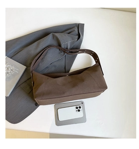 Detail view of brown canvas dumpling bag with adjustable wide eyelet shoulder strap