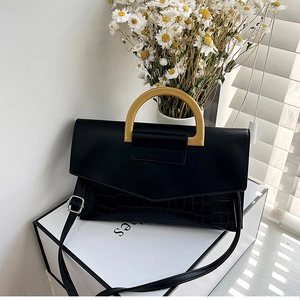 Detail of black crocodile texture bag with distinctive yellow handle and metal buckle