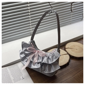 Detail of silver satin hobo bag featuring mesh ruffles and a pink silk bow knot decor