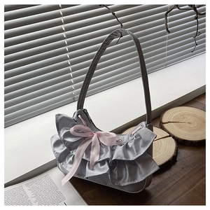 Detailed close-up of silver-grey satin bag with layered ruffles and a pink ribbon bow