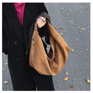 Detailed view of brown suede hobo tote bag featuring a textured finish and metal zipper detail